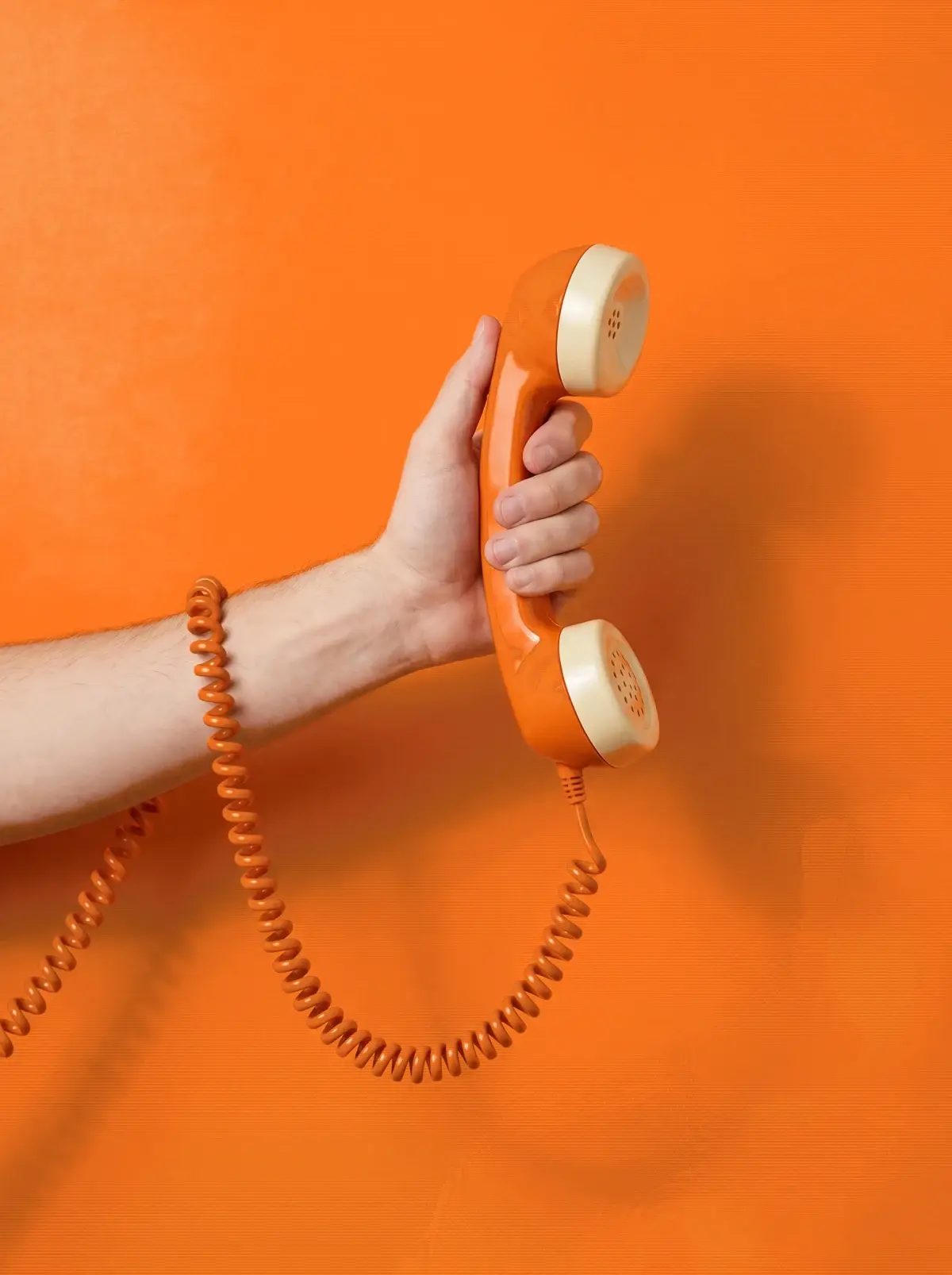 Eine Hand hält einen orangen Telefonhörer